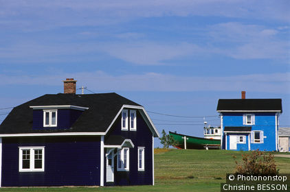 Province du Québec, Iles de la Madeleine, Ile du cap aux Meules, 2 maisons en bois bleu marine et bleu turquoise, dans verdure, barque au fond