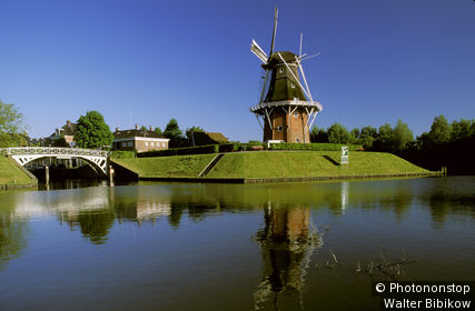 Pays-Bas, Frise, Dokkum, Het Grootdiep, moulin sur tertre verdoyant au bord d'un canal, ciel bleu