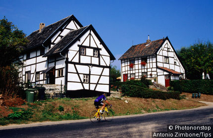 Netherlands, Limburg, Epen, Cyclist passing in front of half-timbered vakwerkhuis.